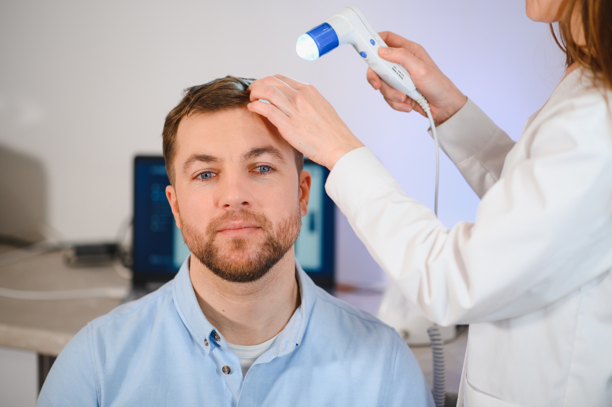 A trichologist examines the hair of a man who begins alopecia.